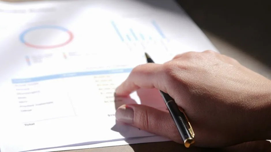 Printed financial charts and a written document spread across a desk beside a pen, suggesting the evidence and reasoning that go into an investment memo