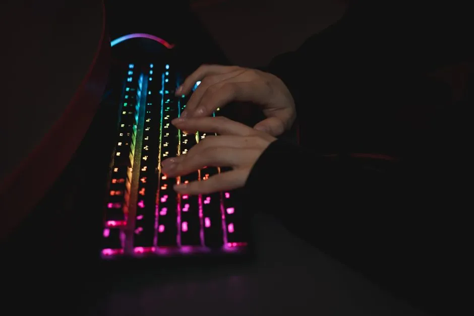 Close-up of hands resting on a mechanical keyboard in a dim office, fingers on the home row, no mouse in frame