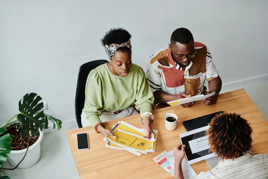 A team gathered around a desk reviewing printed documents and a laptop