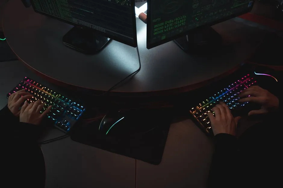 A developer's desk with a mechanical keyboard and code on screen, lit by monitor glow