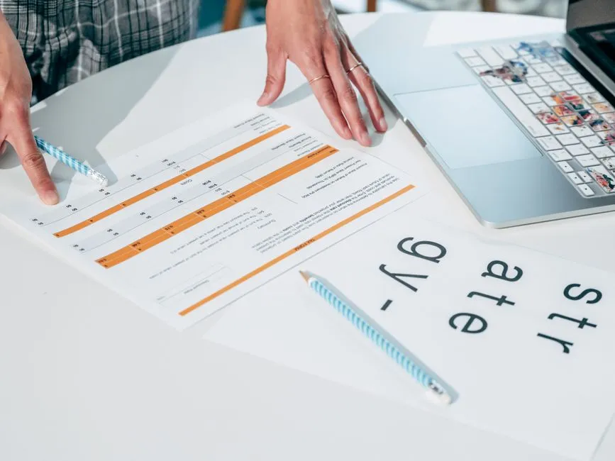 A printed page of plain Markdown text on a desk beside an open laptop
