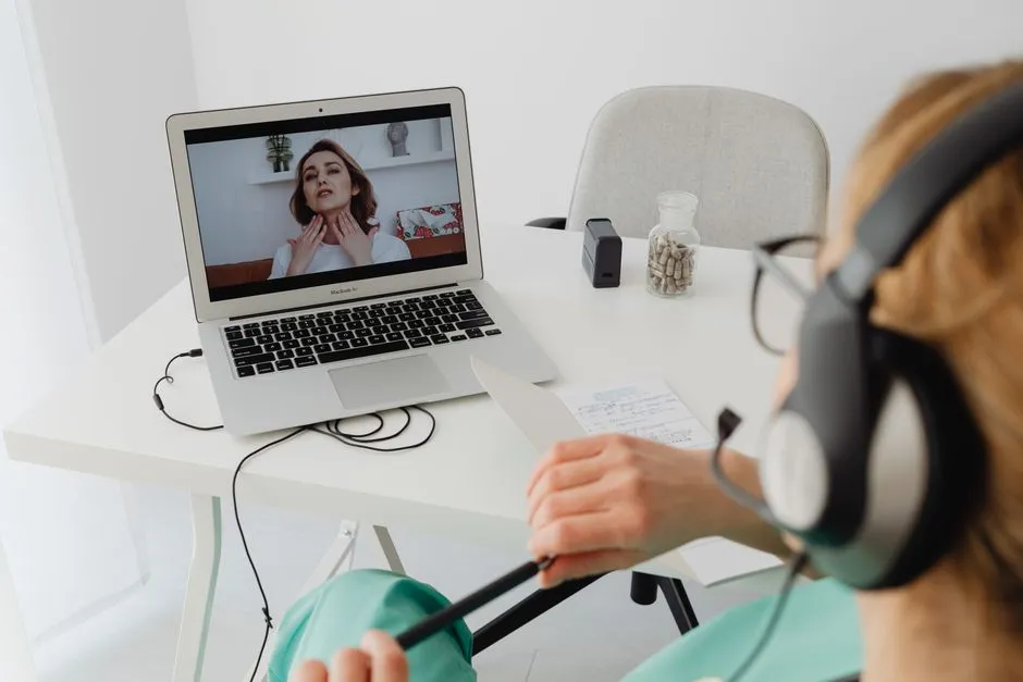 A tidy home-office desk with a laptop on a video call, headphones, and a coffee cup, suggesting a remote worker's daily setup
