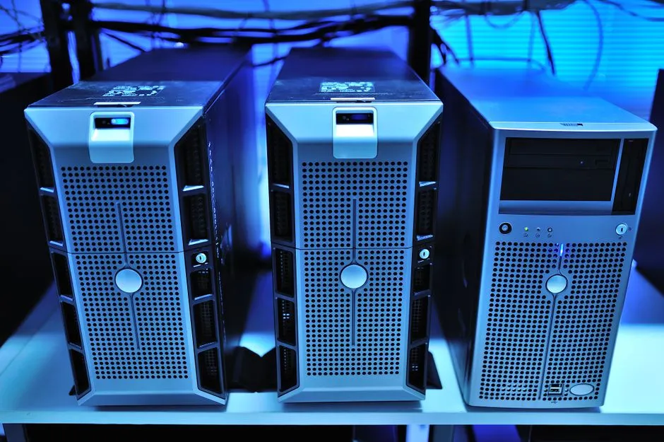 A rack of self-hosted servers in a small server room beside a laptop
