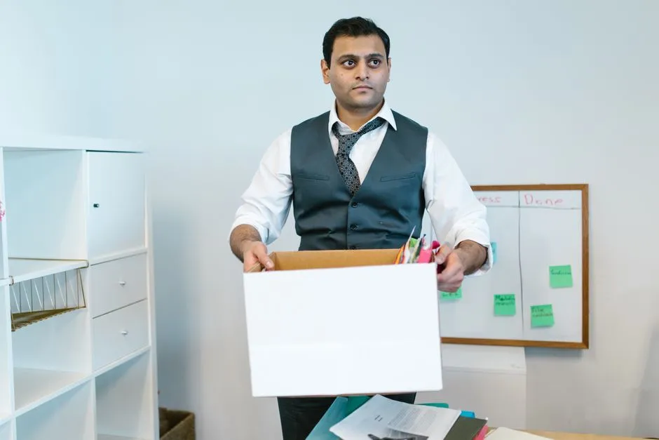 A person at a desk packing documents from an open filing cabinet into a cardboard moving box