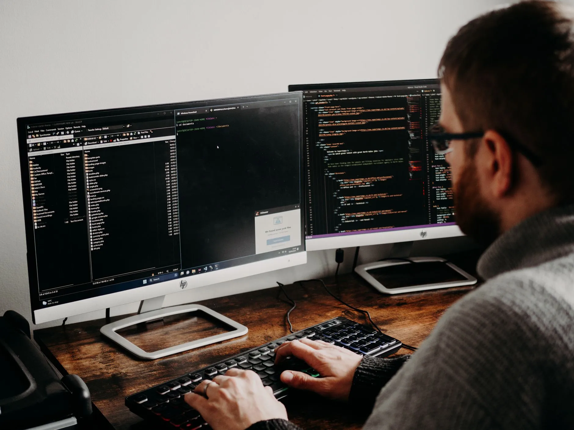 A developer at a desk writing code across two monitors